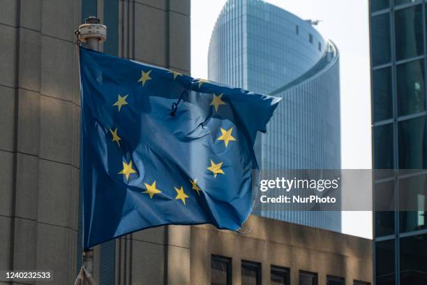 Flag of Europe on flagpole waving in the blue sky on a sunny day among the high buildings in the European capital city Brussels near Brussels North...