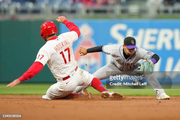 Jose Iglesias of the Colorado Rockies drops the ball on a force play against Rhys Hoskins of the Philadelphia Phillies in the bottom of the third...