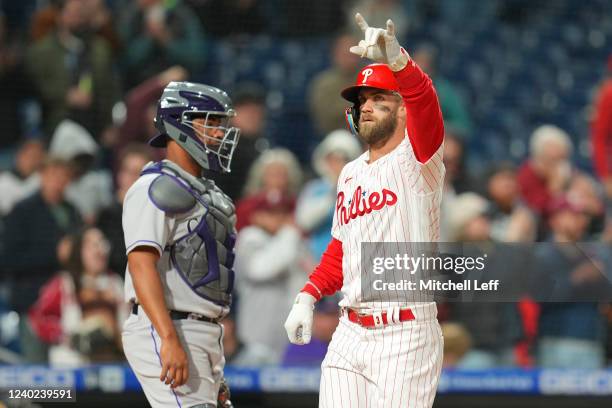 Bryce Harper of the Philadelphia Phillies reacts in front of Elias Diaz of the Colorado Rockies after hitting a solo home run in the bottom of the...