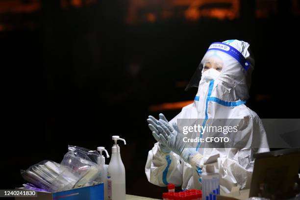 Doctor Xu Qian disinfects his hands at a nucleic acid testing site in Jinan, Shandong Province, China, April 25, 2022. That night, police Kong Shuai...