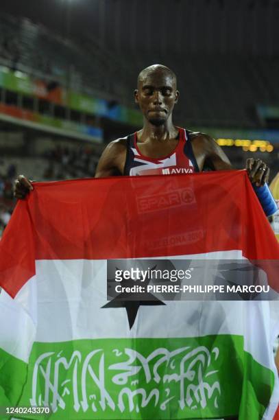 Great Britain's Mo Farah poses with a Somalian flag as he celebrates his victory in the men's 10,000m final at the 2010 European Athletics...