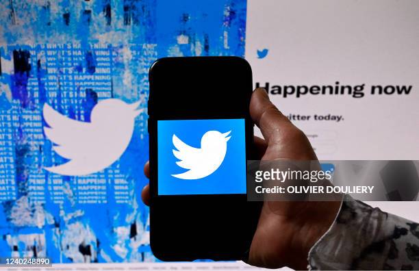 In this photo illustration, a phone screen displays the Twitter logo on a Twitter page background, in Washington, DC, on April 26, 2022. -...