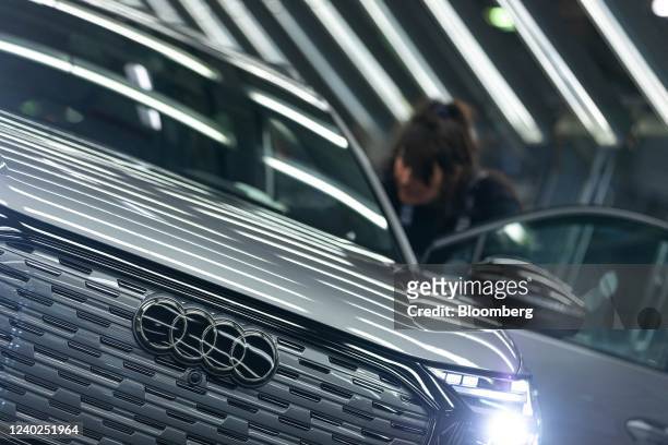 An employee conducts quality control checks on an Audi Q4 e-tron electric vehicle in the light tunnel of the assembly line at the Volkswagen AG...