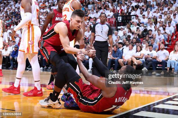 Tyler Herro helps Bam Adebayo of the Miami Heat to his feet during the Round 1 Game 5 of the NBA Playoffs against the Atlanta Hawks on April 26, 2022...
