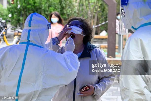 Health worker takes a swab sample from a woman to be tested for Covid-19 coronavirus at a makeshift testing site in Beijing on April 27, 2022. -...