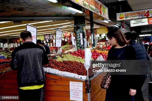 People shop at a market in a suburb of western Sydney on April 27, 2022. - Australia's annual inflation rate hit 5.1 percent in the March quarter,...