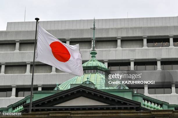 The Japanese flag flutters over the Bank of Japan head office building in Tokyo on April 27, 2022.