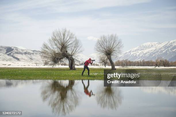 Photographer and trees are reflected on the lake's surface a seen during the spring season in Ovacik district of Tunceli, Turkiye on April 24, 2022.