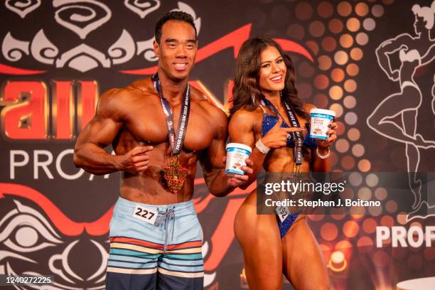 Ponpaisan Ruangsangpen, 1st place, in Men's Physique class and Jill Meret Schmitz, 1st place, in Pro Bikini class poses on stage during the 2022 IFBB...