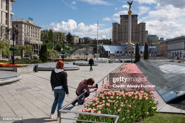 Young woman takes a photo of tulips in blossom on Independence Square on April 27, 2022 in Kyiv, Ukraine. Following Russia's retreat from areas...