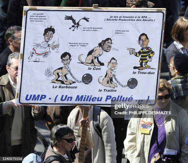 Man holds a placard with caricatures on March 23, 2010 in Lyon, southern France, during a rally as part of a nationwide day of protest against job...