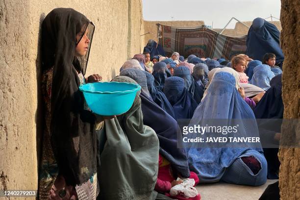 People wait to receive a food donation from the Afterlife foundation during Islam's Holy fasting month of Ramadan in Kandahar on April 27, 2022.