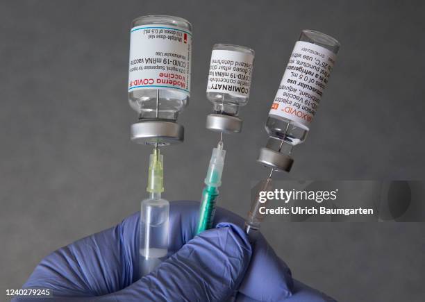 In this illustration photo, taken in a Bonn vaccination center, shows a doctor's hand with medical syringes and the original vaccination vials from...