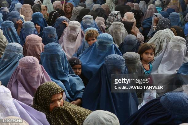 Women with their children wait to receive a food donation from the Afterlife foundation during Islam's Holy fasting month of Ramadan in Kandahar on...