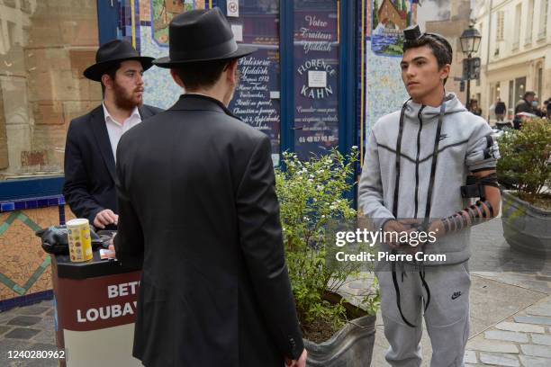 Jewish man wears phylacteries for a prayer on the street Rue des Rosiers on April 27, 2022 in Paris, France.