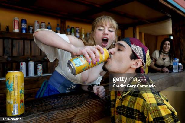 Aura Serena, left, of Fullerton, pours a Golden Road Mango Cart beer into the mouth of Miguel Angel, of San Fernando Valley, at the La Oubliette bar...