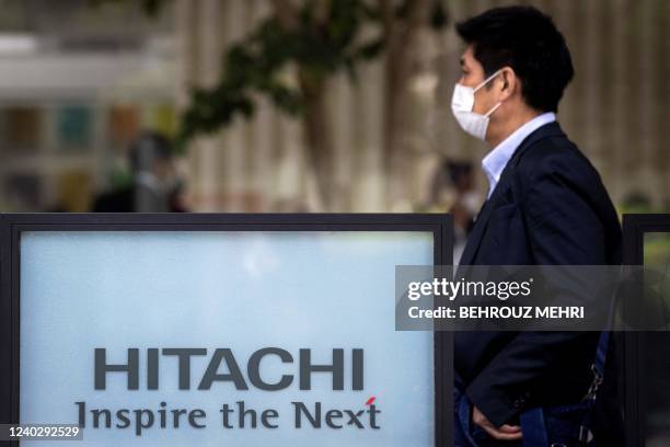 Man walks past the logo of Hitachi in Tokyo on April 28, 2022.