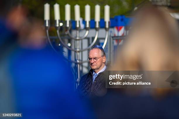 April 2022, Saxony-Anhalt, Magdeburg: Reiner Haseloff , Minister President of Saxony-Anhalt, stands in front of a menorah at the Yom HaShoah...