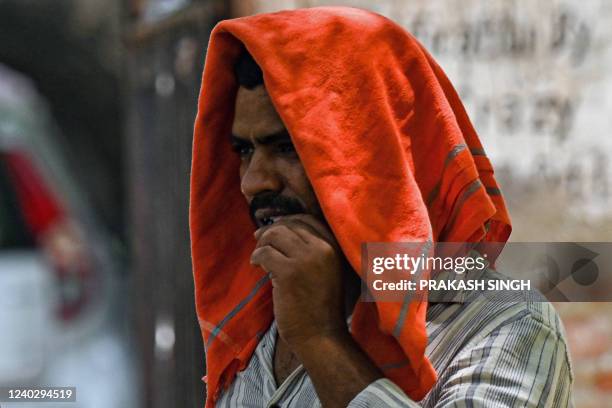 Man covers his head with a cloth to take shelter from heat on a hot summer afternoon in New Delhi on April 28, 2022.