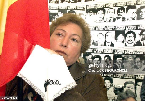 Woman holds a Spanish flag and a hankerchief with the word justice sewn into it. She is participating in a vigil for those that disappeared during...