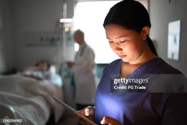 female nurse using digital tablet at hospital room - nurse serious stock pictures, royalty-free photos & images