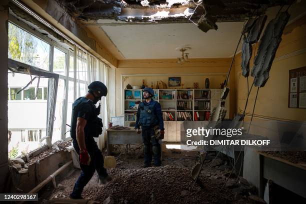 Members of a demining team of the State Emergency Service of Ukraine check for unexploded devices in a school building following Russian shelling in...