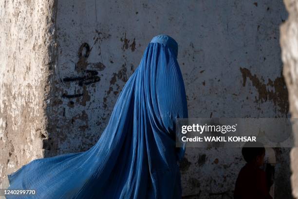 An Afghan burqa-clad woman walks with a child in Kabul on April 28, 2022.