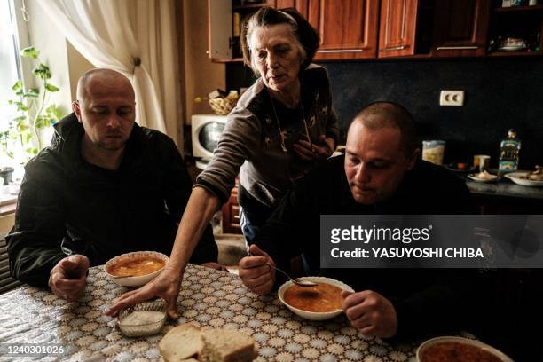 Igor Ugnevenko , the head of Lyman city police, and his colleague are served Ukraine's traditional soup Borscht at the house where they deliver some...