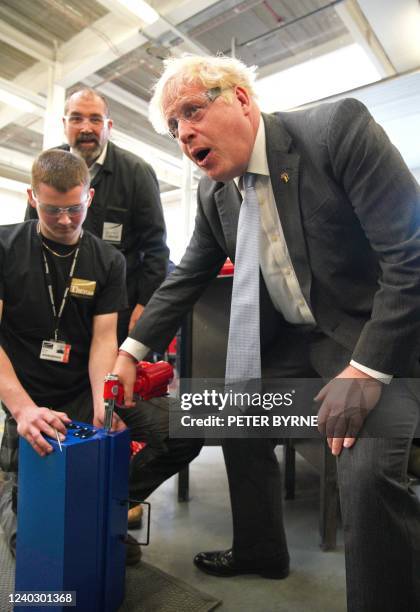 Britain's Prime Minister Boris Johnson uses a rivet gun to fire a rivet into a tool box, which was presented to him during a campaign visit to...