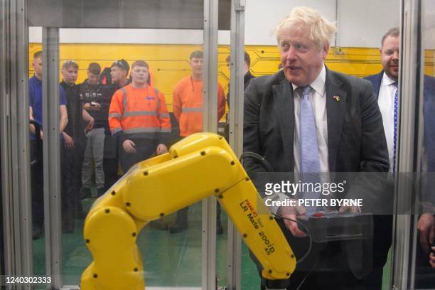 Britain's Prime Minister Boris Johnson uses a robotic machine during a campaign visit to Burnley College Sixth Form Centre in Burnley, north-west...