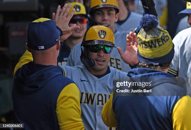 Kolten Wong of the Milwaukee Brewers is greeted by teammates in the dugout after coming around to score on a two run RBI single by Andrew McCutchen...