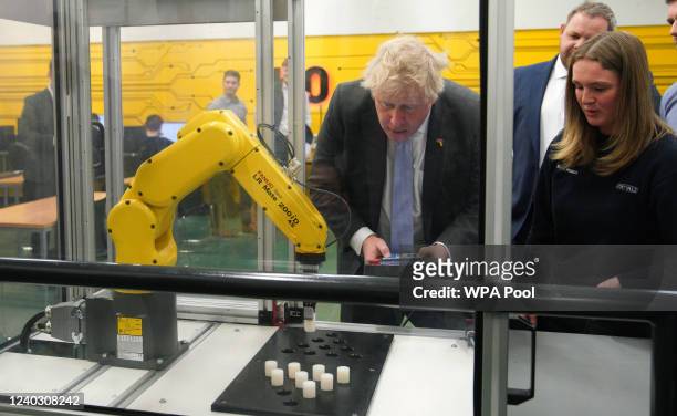 Prime Minister Boris Johnson operates a robotic arm to grab plastic objects during a campaign visit to Burnley College Sixth Form Centre on April 28,...