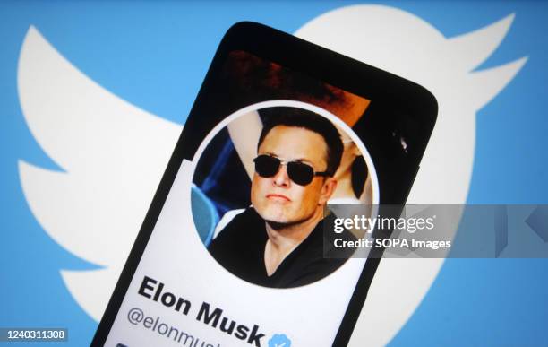 In this photo illustration, Twitter account of Elon Musk is seen on a smartphone screen and Twitter logo in the background.