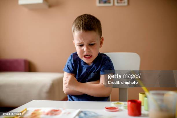 cute little boy coloring with water colors - sad kid in kindergarten stock pictures, royalty-free photos & images