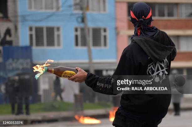 Demonstrator throws a Molotov cocktail at riot police during a protest against the government of Colombian President Ivan Duque to mark the first...
