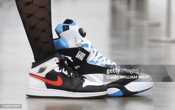 This photo taken in Melbourne on April 28, 2022 shows an assistant placing her sneaker next to a pair of signed Shaquille O'Neil's Reebok Pump Shaq...