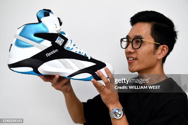 This photo taken in Melbourne on April 28, 2022 shows eBay sneaker expert Alaister Low holding a pair of signed Shaquille O'Neil's Reebok Pump Shaq...