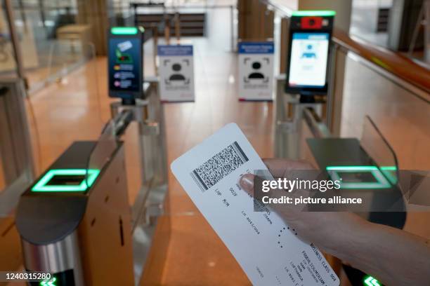 April 2022, Hamburg: A woman holds up a boarding pass in front of the biometric face field recognition system at the security checkpoint in the...