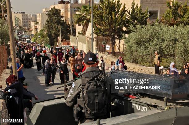 Israeli security forces keep watch as Palestinians cross a checkpoint to reach the city of Jerusalem to attend the last Friday prayers of Ramadan in...