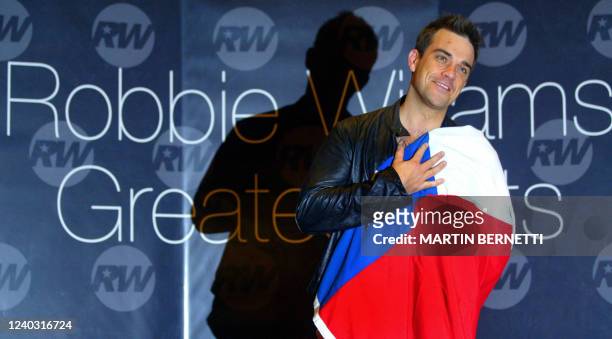 British artist Robbie Williams, poses for photographers with the Chilean flag during a press conference in Santiago, 24 November 2004. Williams...
