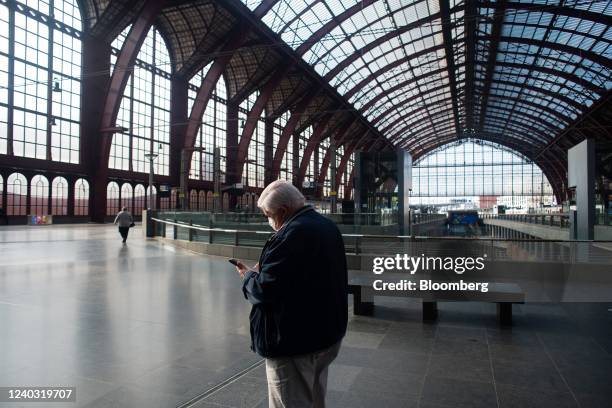 Passenger looks at his mobile phone on an upper level of the train hall at Antwerp Central railway station in Antwerp, Belgium, on Thursday, April...