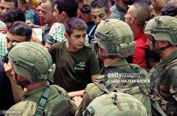 Palestinian boy wearing a T-shirt printed with an M16 rifle is pictured at an Israeli checkpoint on April 29, 2022 in Bethlehem in the occupied West...