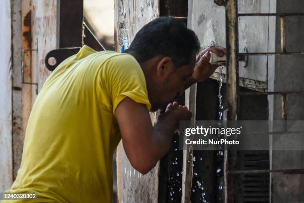 Man is seen drinking water from a road side water cooler to relieve himself of summer heat , at a street side in Kolkata , India , on 29 April 2022 ....