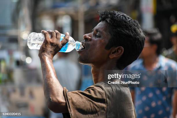 Man is seen drinking water to relieve himself of summer heat , at a street side in Kolkata , India , on 29 April 2022 . Indian meteorological...