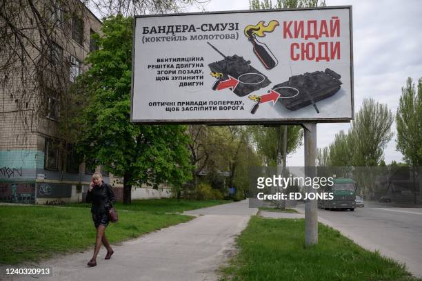 Woman walks past a billboard advising where to target tanks when throwing molotov cocktails, in Zaporizhzhia on April 29 on the 65th day of the...