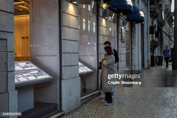 Couple stop to browse listings in the window of a real estate agent's office in the Bairro Alto district of Lisbon, Portugal on Wednesday, April 27,...