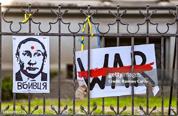 Illustrations depicting Russian President Vladimir Putin and protesting against the war in Ukraine are displayed on railings in a street near the the...