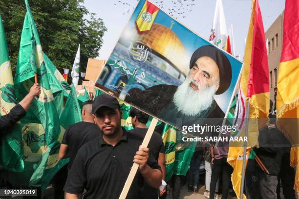 An Iraqi protester lifts a placard depicting Jerusalem's Al-Aqsa Mosque and Iraq's top Shiite cleric Grand Ayatollah Ali al-Sistani during a rally to...