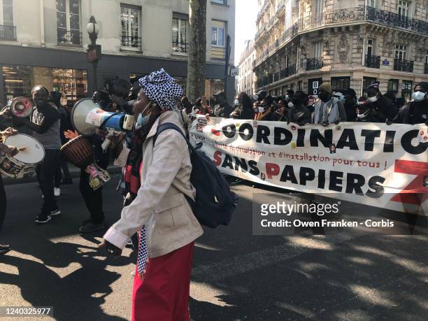 Men play African music and a woman speaks as a group of mostly African ethnic people march along the boulevard between Place de la Republique and...