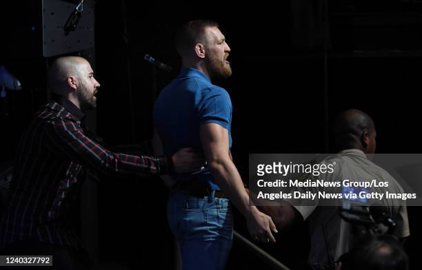 Las Vegas, CA Conor McGregor is restrained after throwing objects at opponent Nate Diaz during an altercation during the UFC 202 Press Conference at...